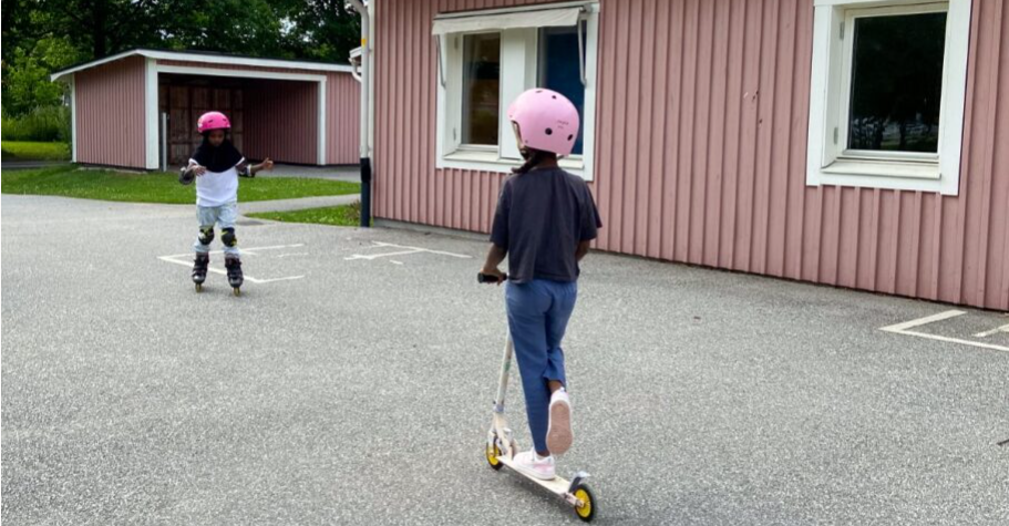 pojke som åker sparkcykel,  i bakgrunden en flicka som åker inlines