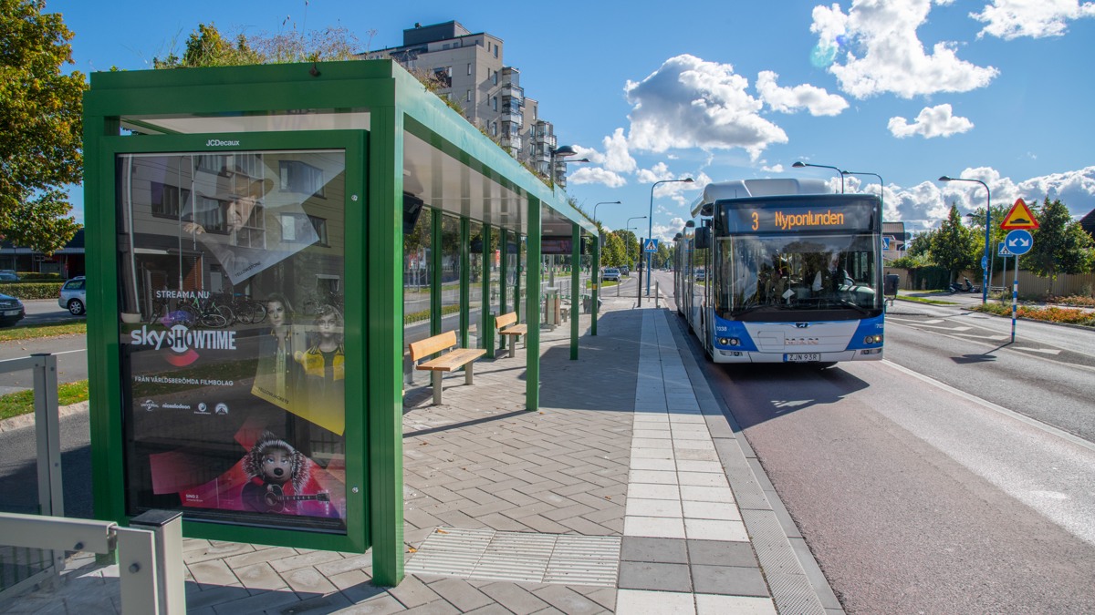 En buss anländer vid en hållplats med det gröna väderskyddet, som är karakteristiskt för Citylinjen.
