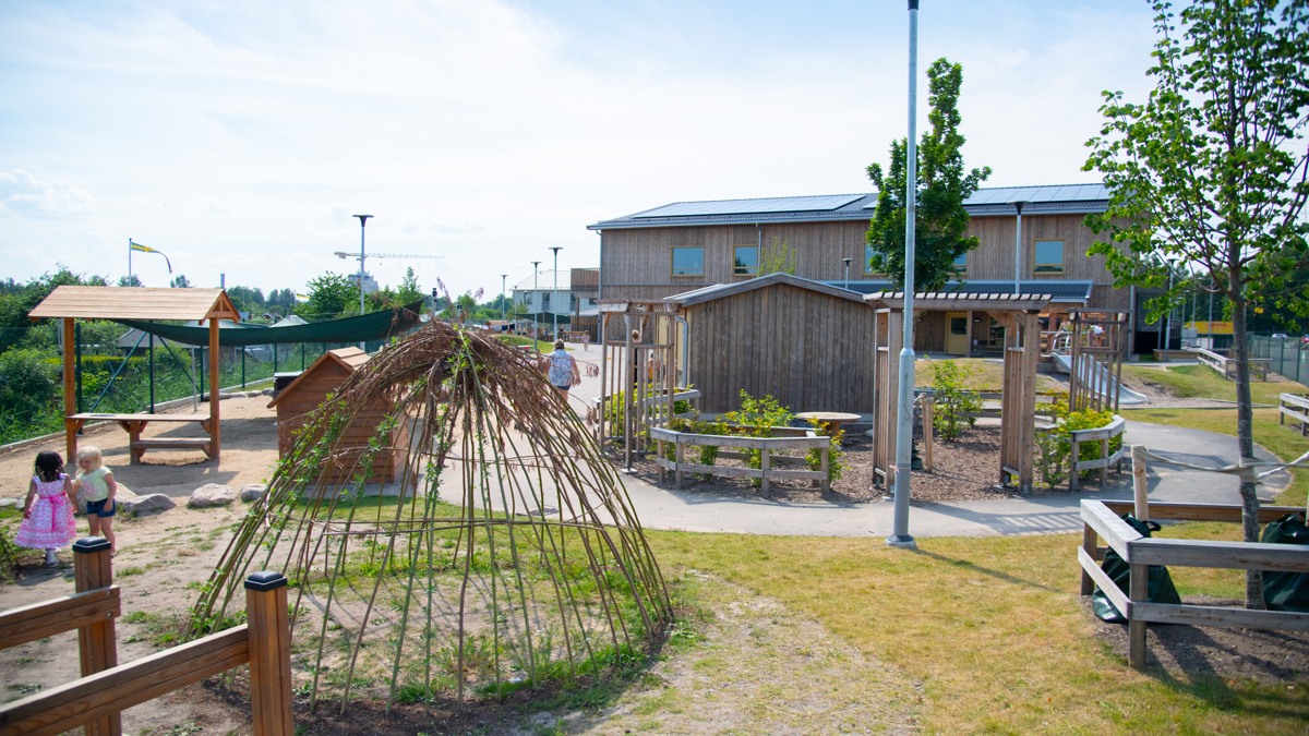 En lekplats för barn i en park med en lekplats i bakgrunden.