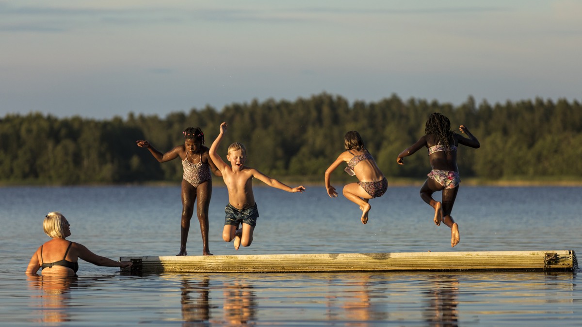 En grupp människor som hoppar från en flotte ner i en sjö.