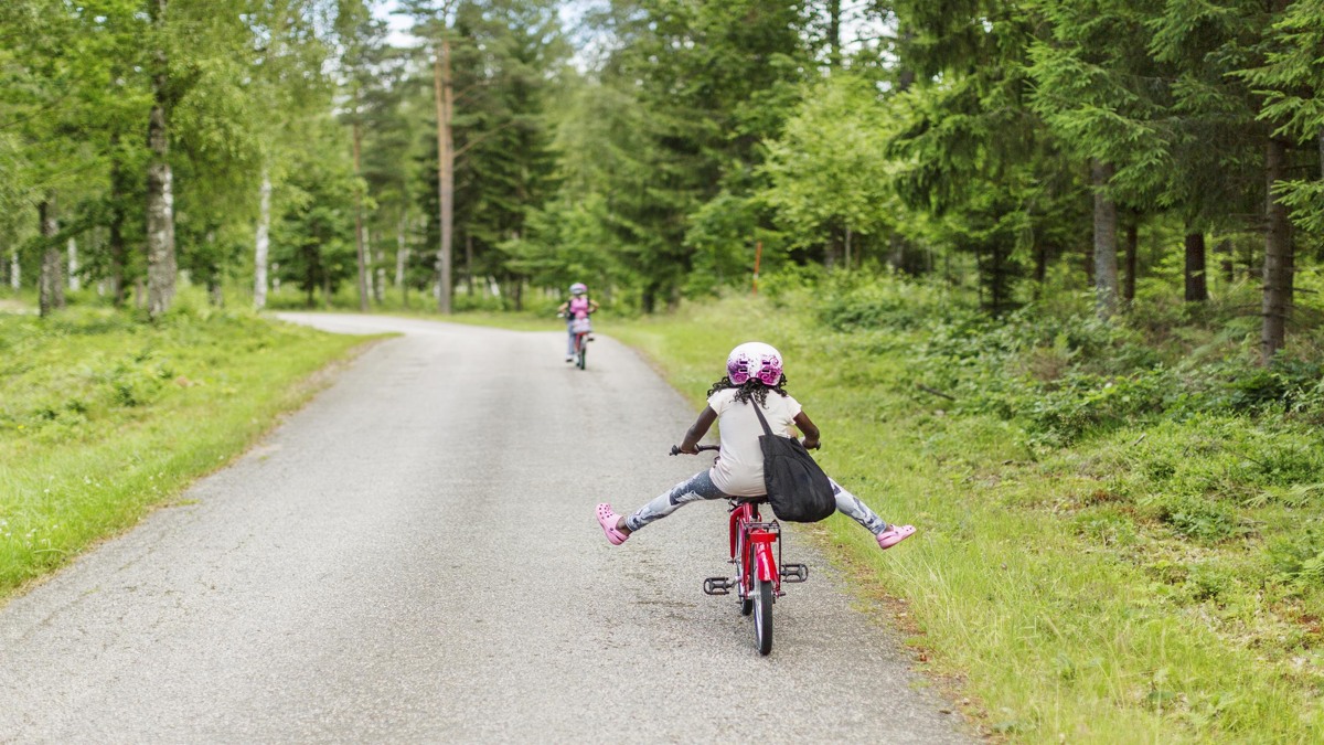 Två barn som cyklar på en grusväg.