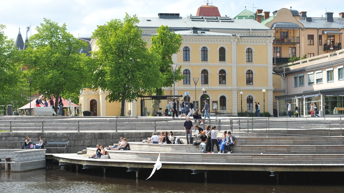 En grupp människor som sitter på en brygga intill ett vattendrag.