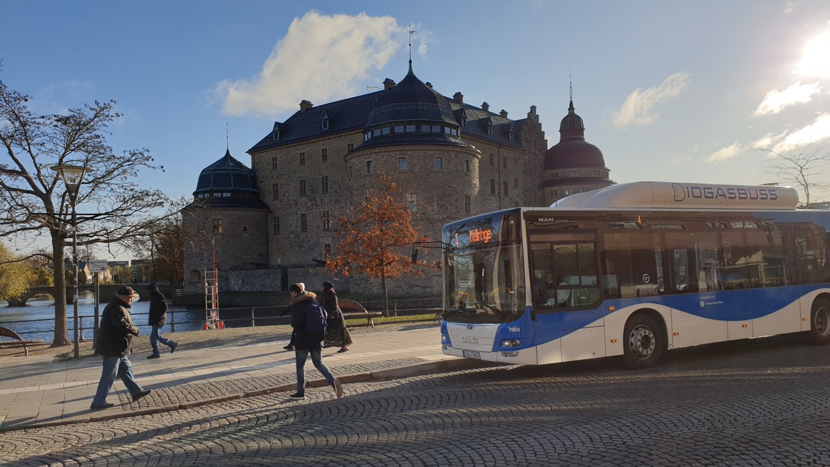En blå och vit buss parkerad vid sidan av en väg.