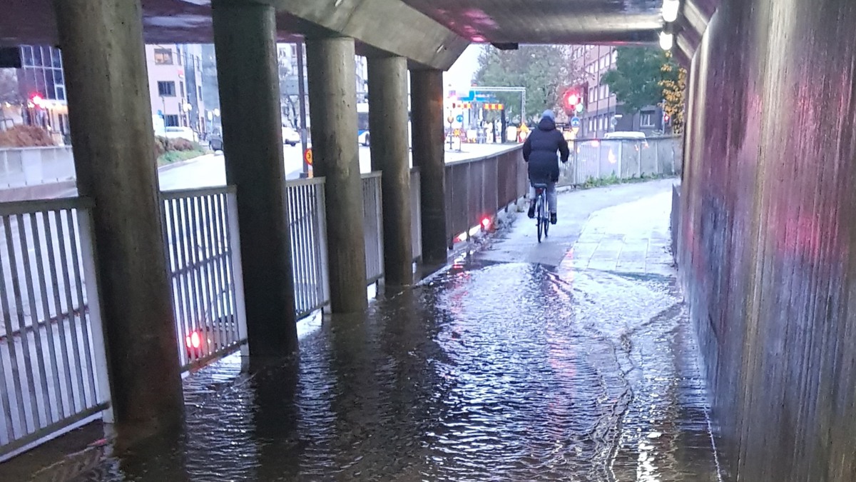 En person på cykel, genom en översvämmad tunnel.