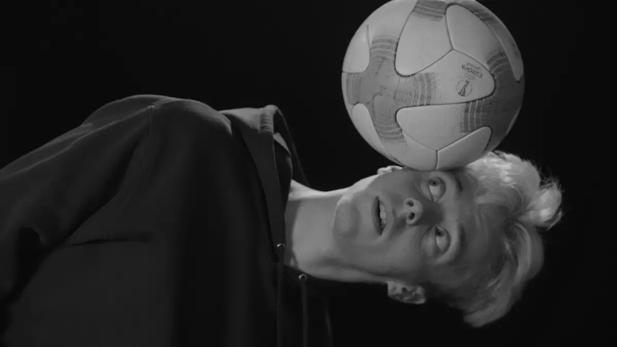 Ung man balanserar en fotboll på huvudet.