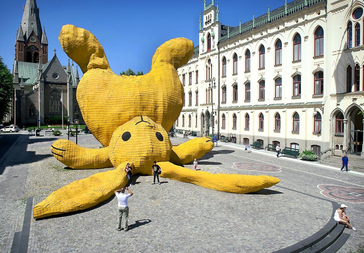 Tänk dig att du tar en promenad på stan och när du närmar dig Stortorget så börjar du få syn på en gigantisk gul skulptur. Desto närmare du kommer så inser du att det är en liggande överdimensionerad gul kanin med svarta ögon och mun. Kaninen ligger med huvudet, öronen samt armarna ner mot marken och resten av kroppen upp mot skyn. I bakgrunden syns Nikolaikyrkan samt Rådhusets byggnad som ser ut att vara lika högt som kaninen. Framför kaninen står tre vuxna turister och tar kort, människorna ser pyttesmå ut jämfört mot den gula kaninen och kvinnan som lutar sig mot ena örat är nästan lika lång som örat.