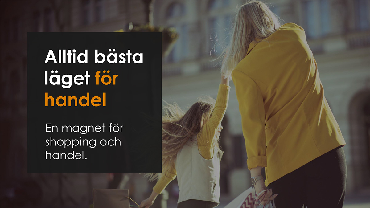 En kvinna och ett barn går hand i hand på en shoppinggata. Kvinnan bär en gul jacka och håller shoppingpåsar. Texten på bilden lyder: "Alltid bästa läget för handel. En magnet för shopping och handel."