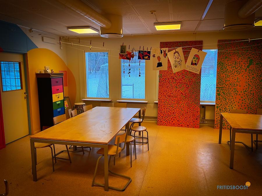 Rum med bildskärm bord och stolar samt två soffor och soffbord