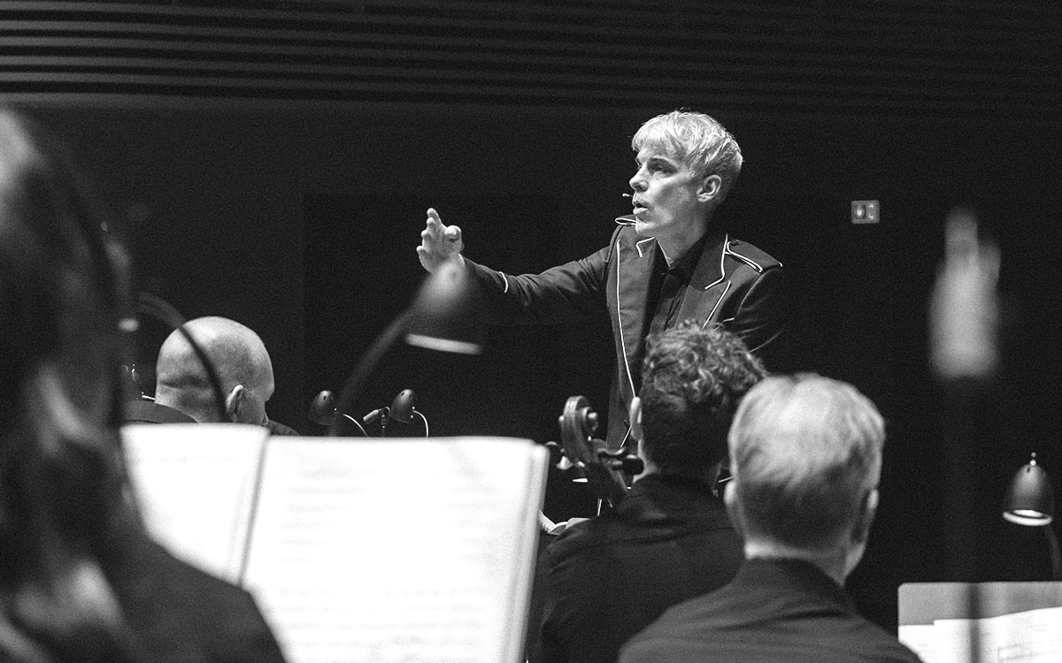Foto på Martin Fröst när han dirigerar en orkester på scen.