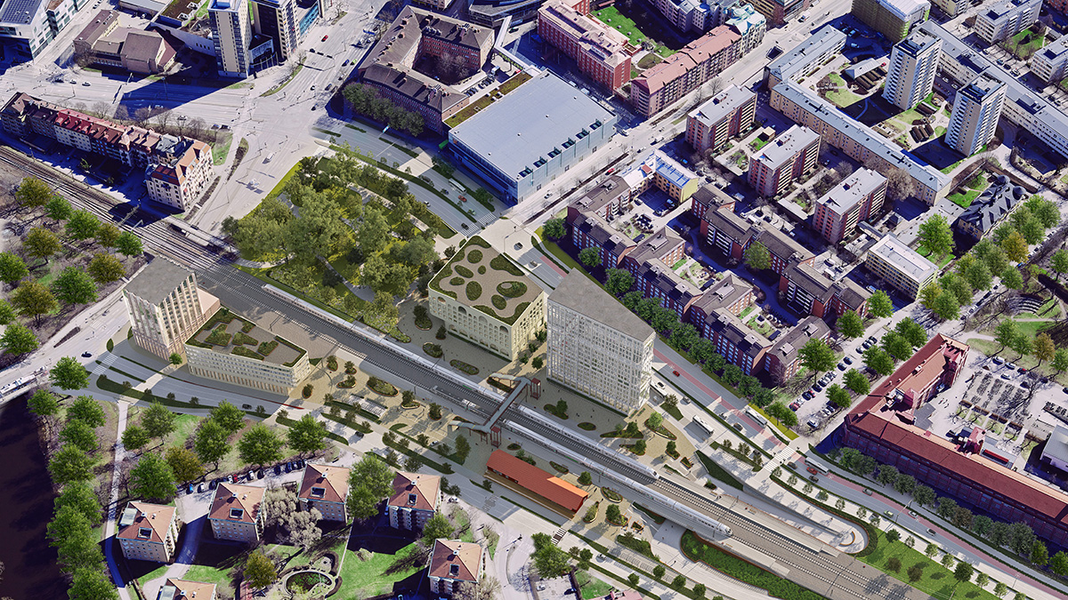 Flygvy över ett stadsområde med järnväg och station i centrum.